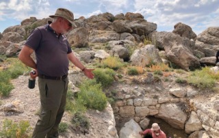 Archaeologist discussing a nearby ancient tomb near the Pınarbaşı excavation site in Turkey, showcasing historical discoveries.