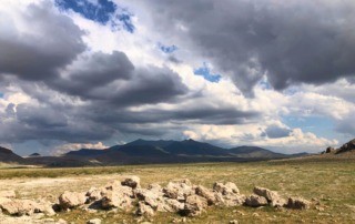 Expansive landscape surrounding the Pınarbaşı archaeological site in Turkey, featuring hills and dramatic clouds.