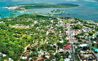 A vibrant aerial shot of Kolonia Town, featuring the coastline and islands of Pohnpei.