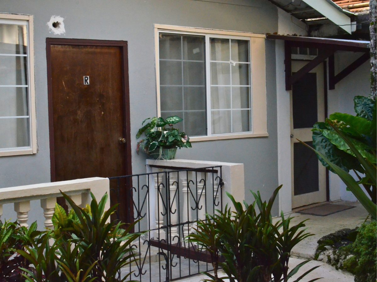 A view of the student accommodations in Pohnpei, featuring a cozy exterior with plants and a small veranda.