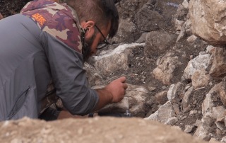 Archaeology student performing meticulous excavation work, using tools to carefully brush through soil in Bostel di Rotzo, Italy.