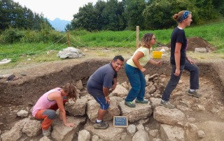 Archaeology students enjoying a moment of fun during an excavation at Bostel di Rotzo, Italy, posing in a row.