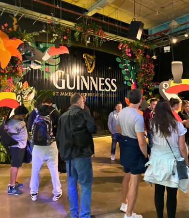 Group of visitors exploring the Guinness Storehouse at St. James's Gate Brewery in Dublin, Ireland, with colorful decorations and branding