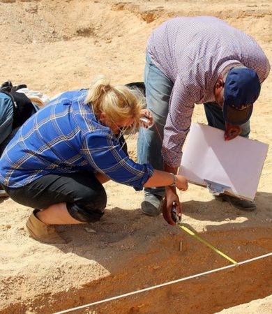 Two archaeologists, one Egyptian and one foreign, working together to measure and map at a site in Amarna.