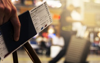 A close-up of a hand holding a boarding pass and passport at the airport, symbolizing travel preparation.