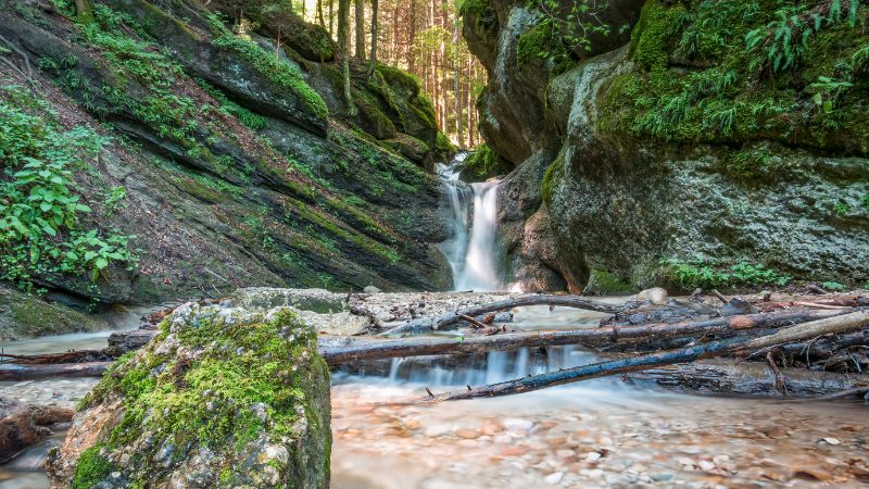 A serene waterfall in the Seven Ladders Canyon near Brasov, Romania, surrounded by lush green forest, a free time option from IFR's Sanpetru Bioarchaeology Program.