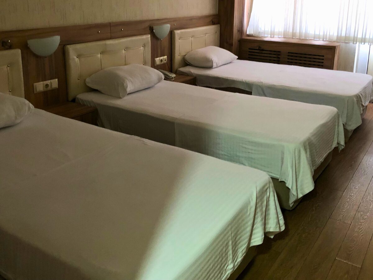 A clean and well-maintained room with three single beds, showcasing the shared accommodations provided for participants at the Turkey Pinarbasi field school.