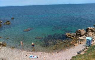 Clear blue waters of the public beach in Mytilene, Greece, with swimmers enjoying the shoreline.