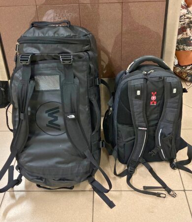 Two pieces of essential field gear for archaeology students – a large black duffel bag and a smaller backpack, packed and ready for the field.